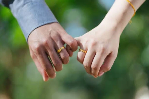 Two hands intertwined with wedding rings, symbolizing a committed and intimate relationship.