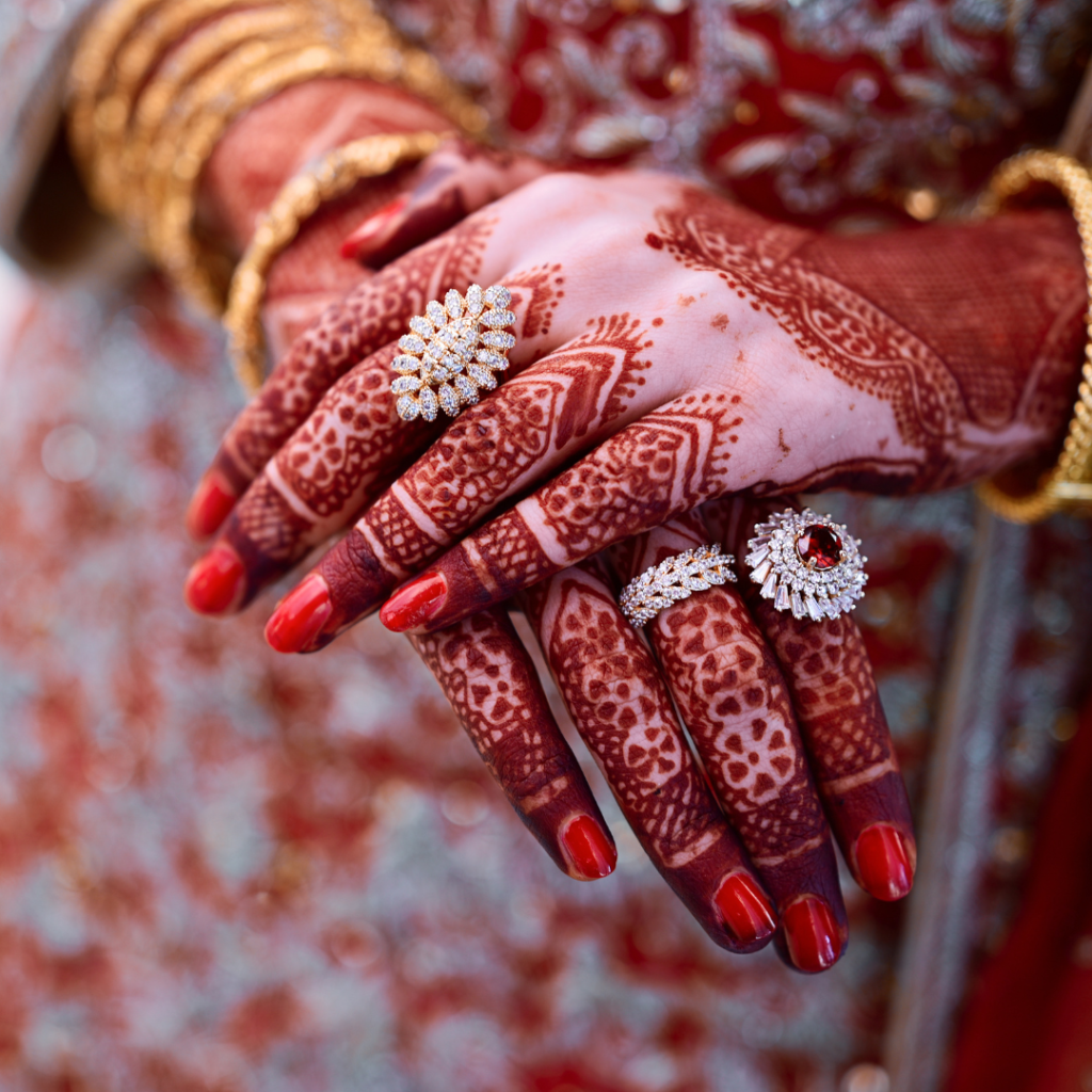 Two hands decorated with mehndi, holding each other tightly, representing the strength and support within an Indian marriage.