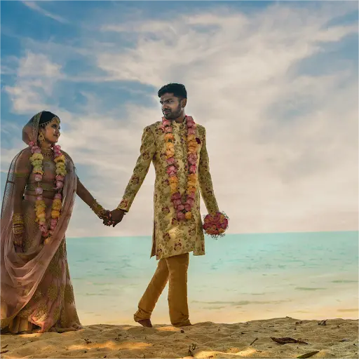 A modern Indian couple exchanging vows under a mandap decorated with flowers and fairy lights, representing the blending of traditional and contemporary elements in Indian weddings.